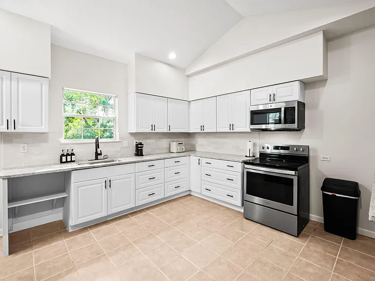 Spacious U-shaped kitchen with ample cabinet storage, stone-look counters, and stainless steel range and microwave.