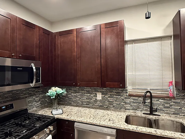 Well-appointed kitchen with ample wood cabinetry, granite-style counters, mosaic backsplash, and stainless appliances.