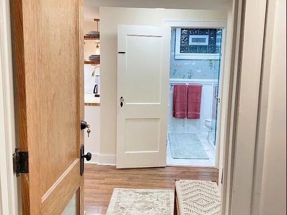 View from entry through hallway with storage to bathroom. Kitchen, dining, living is to the left. Bedroom to the right