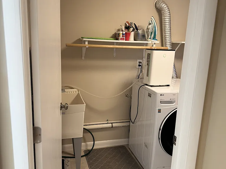 Basement laundry room with washer, dryer, utility sink, and tankless hot water system.