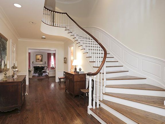 Another view of the impressive FRONT ENTRY showing its gracefully curved staircase leading to the second floor and its wide corridor leading to the spacious formal LIVING ROOM .