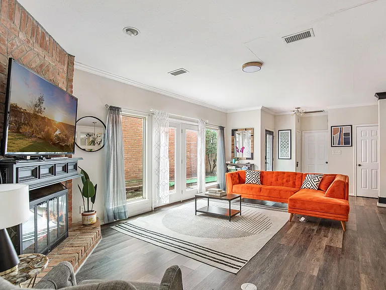 Spacious living room with a brick fireplace wall, large windows, and French doors that open to the patio area.