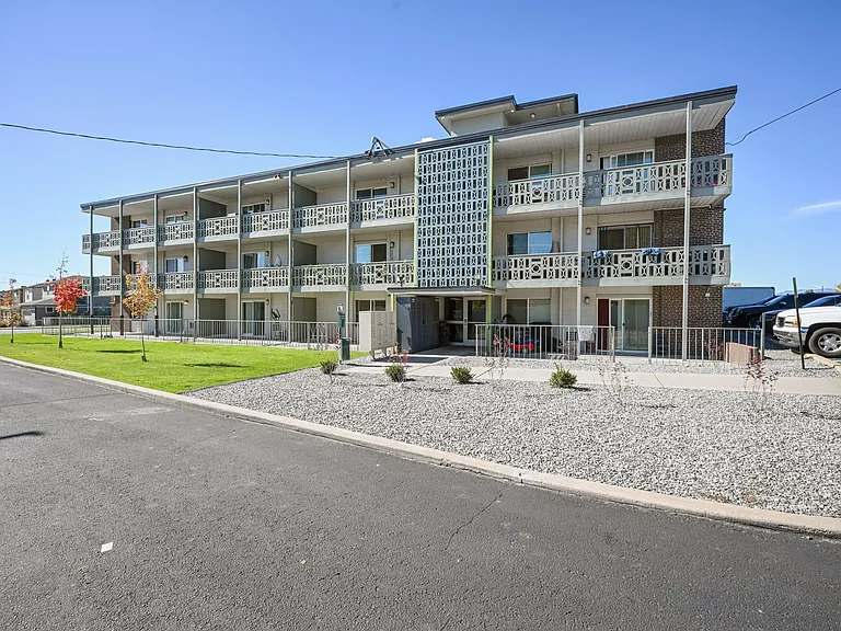 Charming three-story apartment building with modern balconies and landscaped surroundings, offering an inviting residential atmosphere.