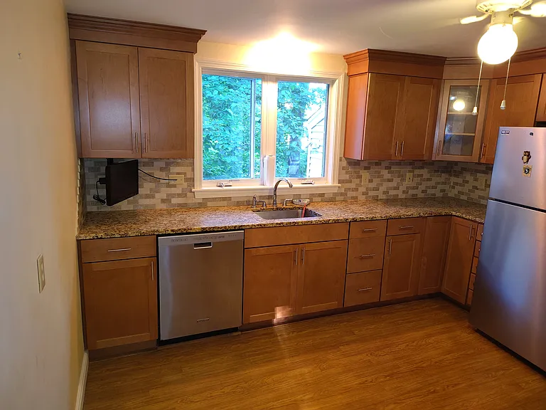 Kitchen showing stainless steel refrigerator, wooden cabinets, stainless steel dishwasher, ceiling light/fan.