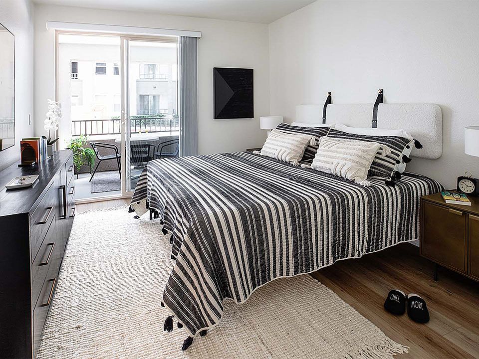Spacious apartment bedroom with wood-style flooring and balcony access.