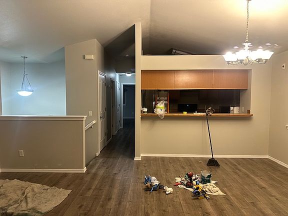 The view of the upstairs from in front of the windows, looking into the kitchen, hallway to the bathroom and 2 bedrooms, and stairs going down.