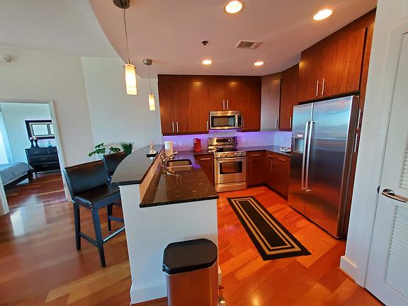 Kitchen with granite counter tops, stainless steel appliances (fridge, microwave, stove, oven, dishwasher, and sink with garbage disposal), and breakfast bar with stools. Condo come furnished and decorated as pictured.