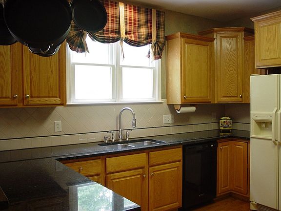 Kitchen features stained wood cabinets and new granite countertops