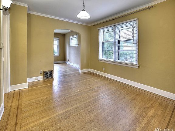 Dining room features crown molding, leaded glass windows, and hardwood floors. This view is looking towards the living room. 