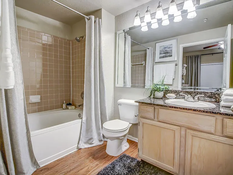 Master bathroom with soaking tub, tile backsplash, large mirror and wood style flooring