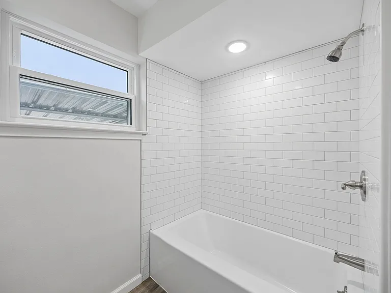 Bathroom featuring a white subway tile shower surround with brushed nickel fixtures, a built-in tub, and a recessed ceiling light
