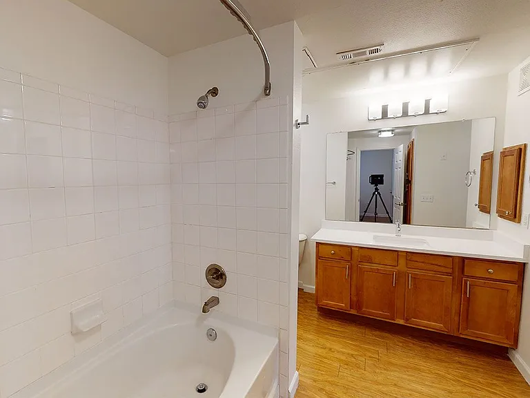 Apartment bathroom with wood-style flooring. Quartz-style countertops (shown here) are available in select homes.