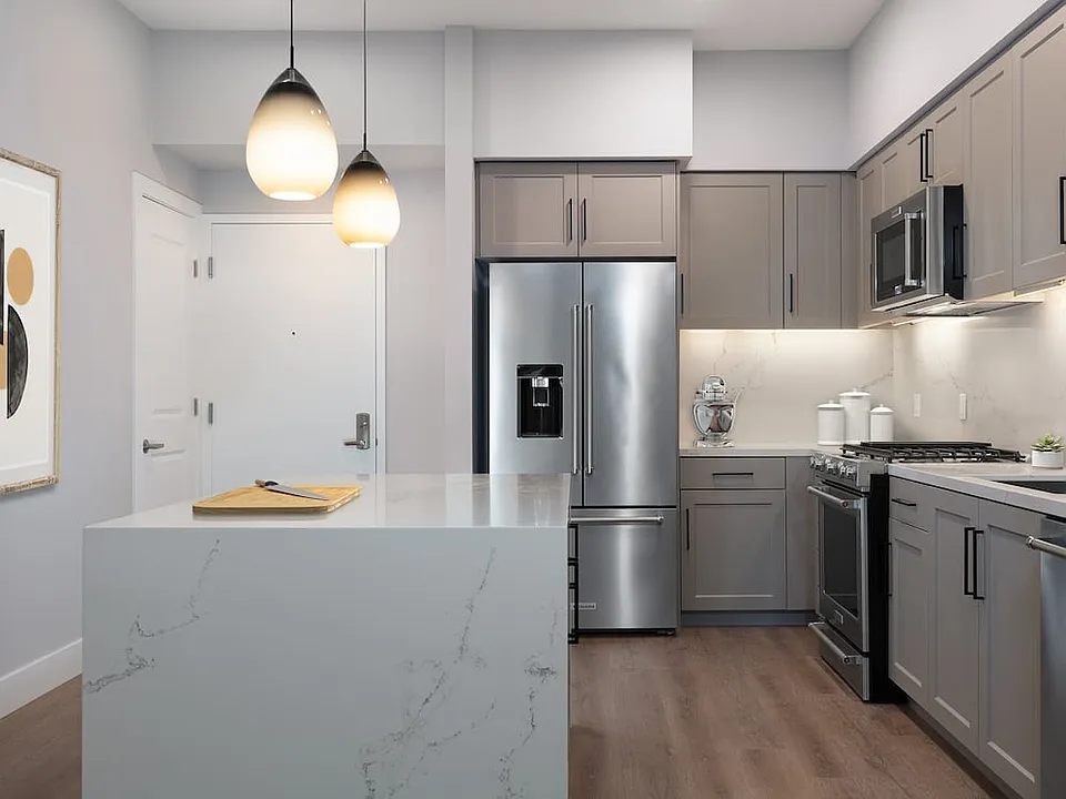 Signature Collection kitchen with upgraded stainless steel appliances, grey cabinetry, white marble countertops and backsplash, and hard surface flooring