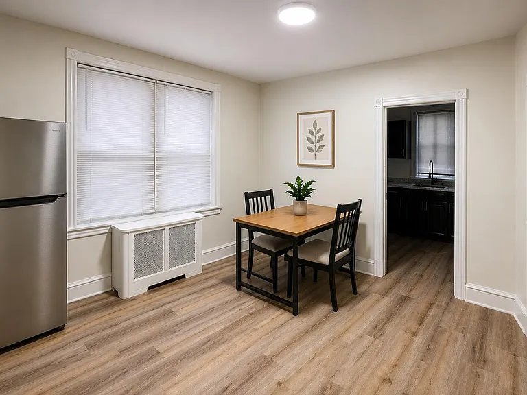 Eat-in dining area with a 2-seat table, window with blinds, and easy access to the kitchen; includes a full-size fridge.