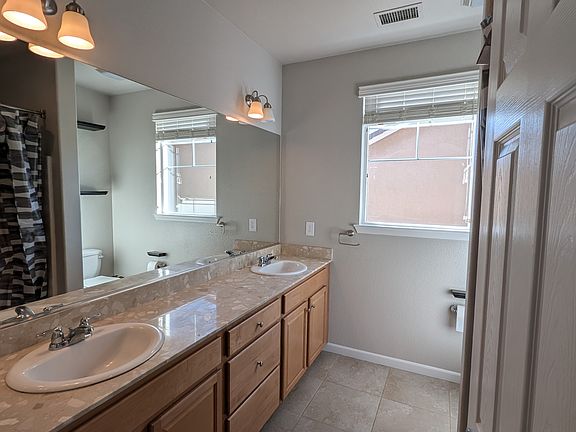 Bathroom with south facing window. There is a bathtub, two sinks, and one toilet. Shelves included.