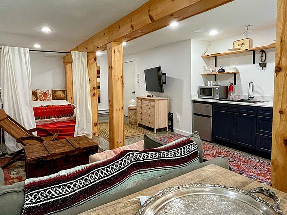 In the front of the room is the dining area, living area and kitchen.