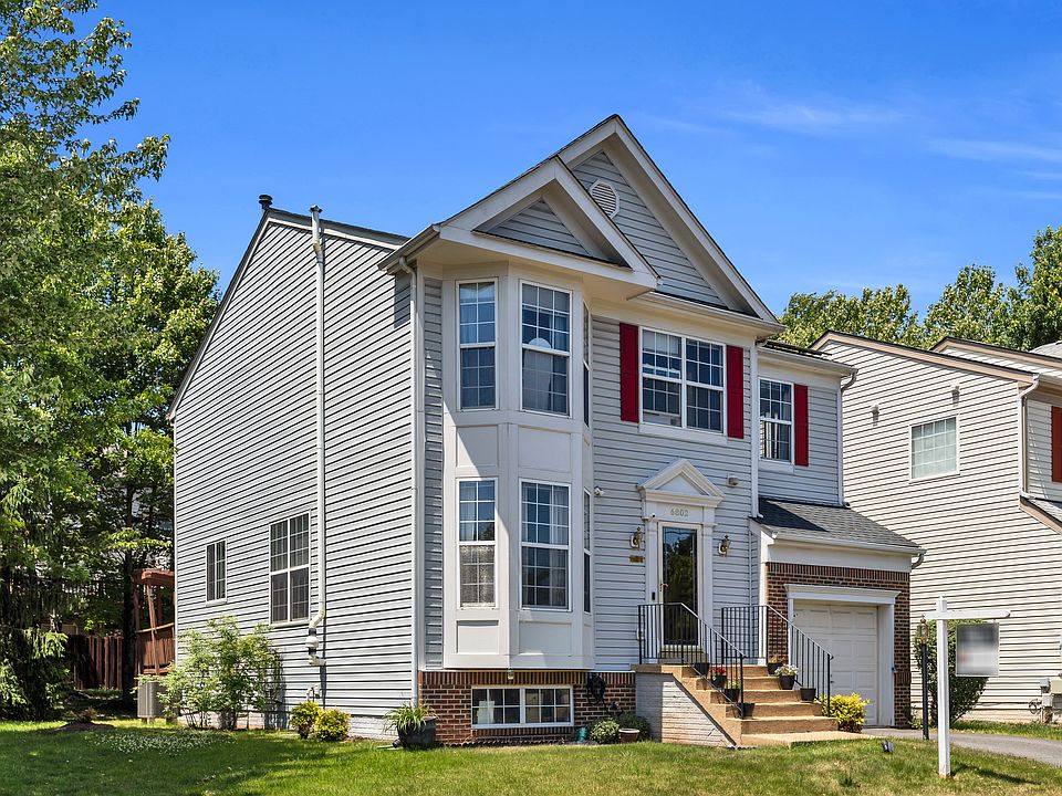 Charming colonial with classic red shutters and lush front landscaping