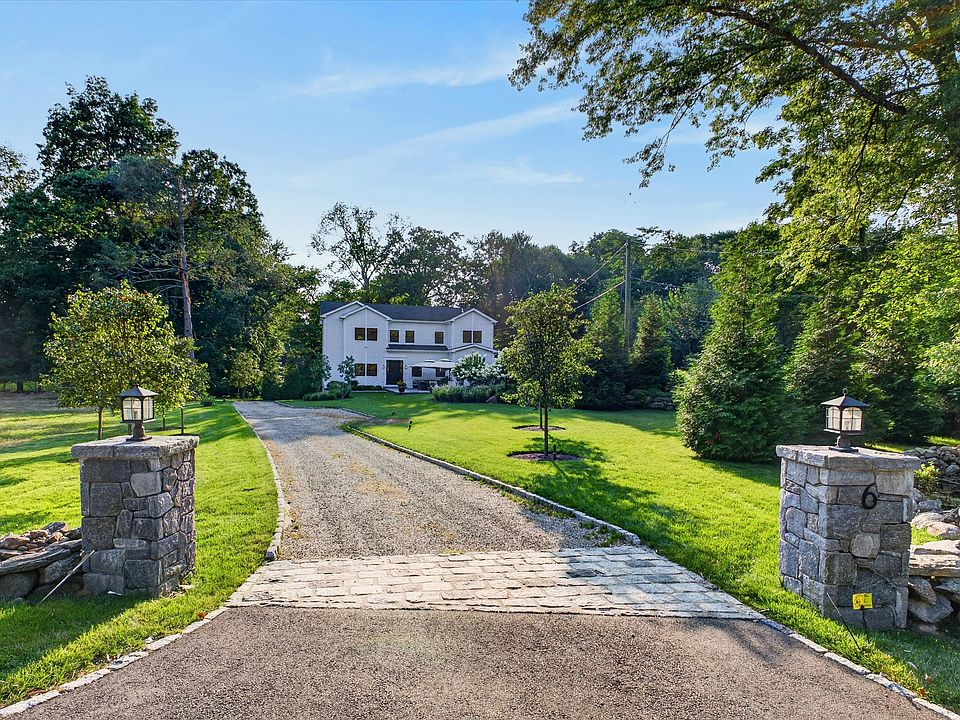 Nestled on a quiet parcel in Westport, a long cobblestone-accented driveway leads to a light-filled seasonal retreat framed by pristine lawn and soaring trees.
