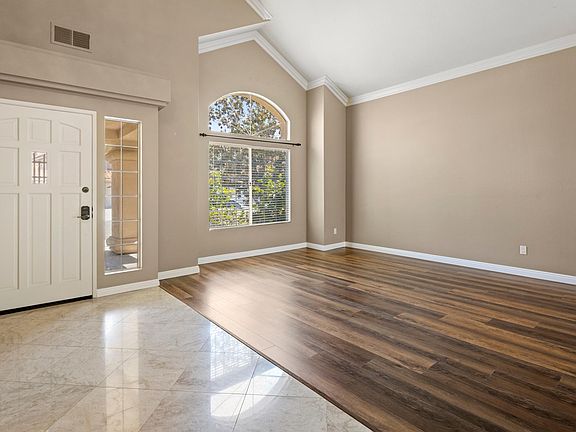 Open sitting and dining area with high ceilings and chandelier.