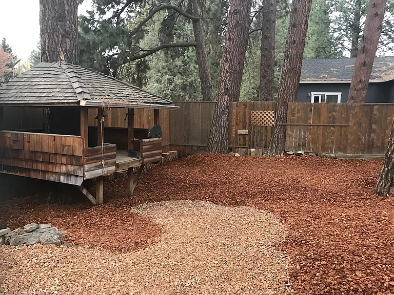 Fenced backyard with treehouse