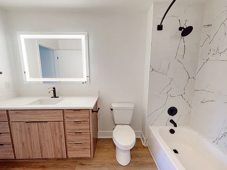 Apartment bathroom with wood-style flooring and LED vanity mirror.