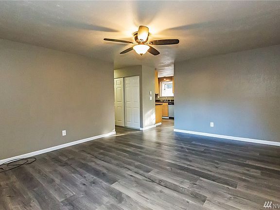 Notice the ceiling light and fan in the living room.  Looking ahead is the hallway leading to the bedrooms, and the entry to the kitchen.