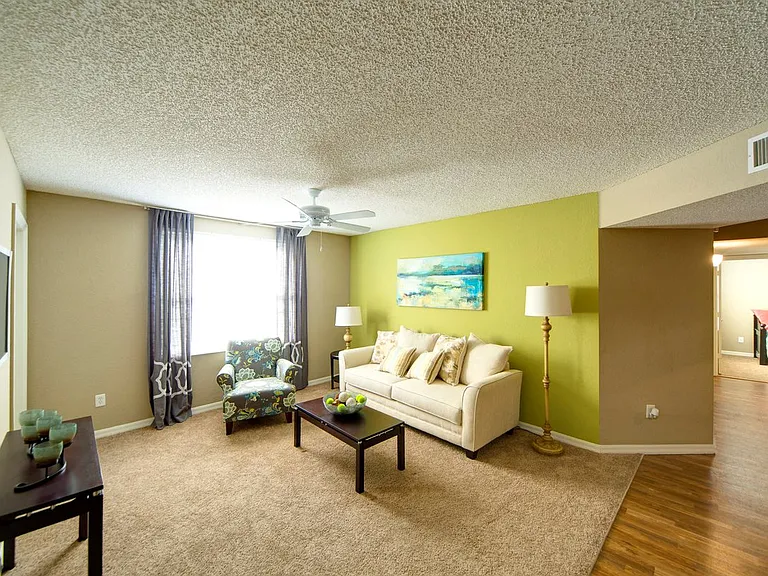 Living room with bright windows and a ceiling fan at Gregory Cove in Jacksonville, FL