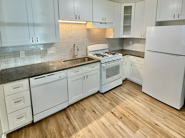 Gourmet-ready kitchen_ white shaker cabinets & granite countertops maximize prep space - subway tile backsplash & sink light create a bright hub for effortless entertaining