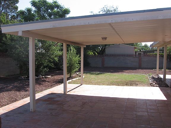 Large, landscaped back yard with large covered patio and mature vegetation.