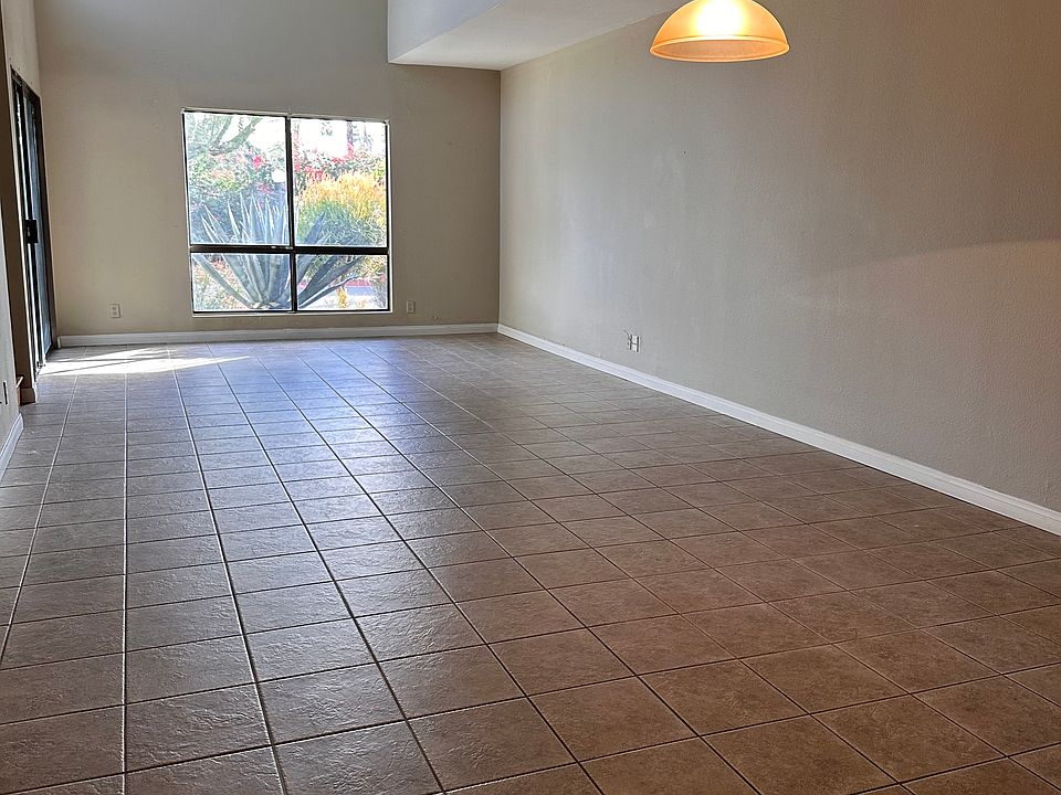 Bright living and dining area with high ceilings, tile flooring, and large window bringing in abundant natural light.