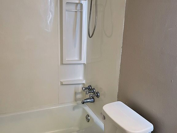 Bathroom with showerheads and nook for bath essentials.