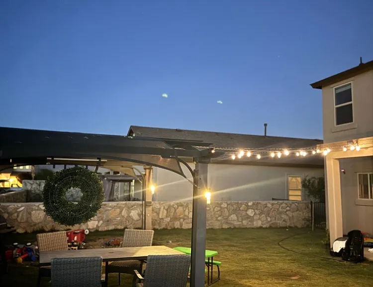 overall of backyard with pergola and solar lights on