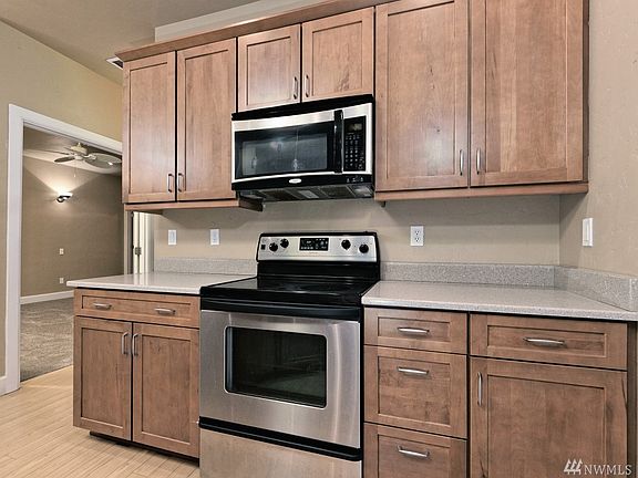 Another view of the kitchen with solid-surface countertops and nice cabinets. Beyond is the door to the Master bedroom!  And around the corner to the right is the utility room and door to the 3-bay garage.