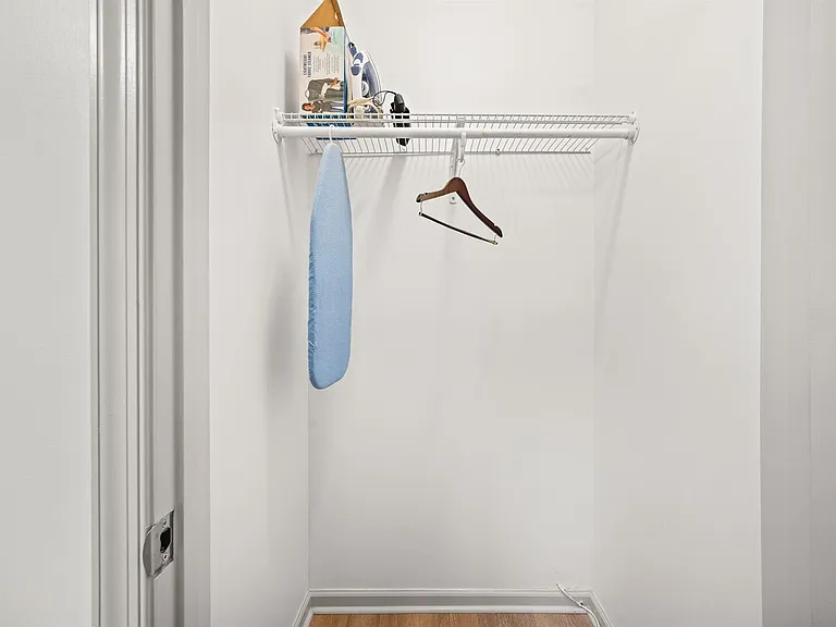 Reach-in closet with a wire shelf and hanging rod, offering convenient storage for clothing and household essentials.