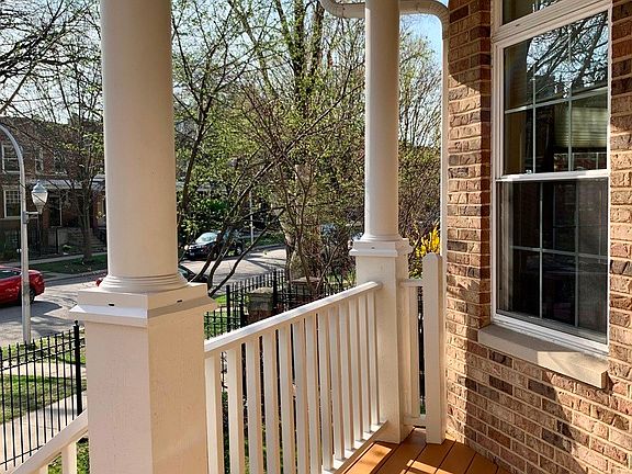 The warm and welcoming porch looks a quiet neighborhood streetscape.