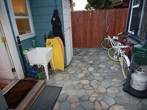 Shared back courtyard with an outdoor sink, outdoor shower (not pictured), a cabinet with washer/dryer, and space for bike storage.
