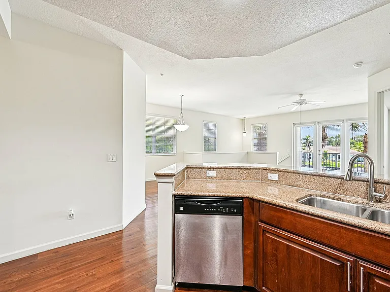 Bright, open-concept living area showcasing sleek granite countertops, stainless steel appliances, and a warm, inviting wooden floor.