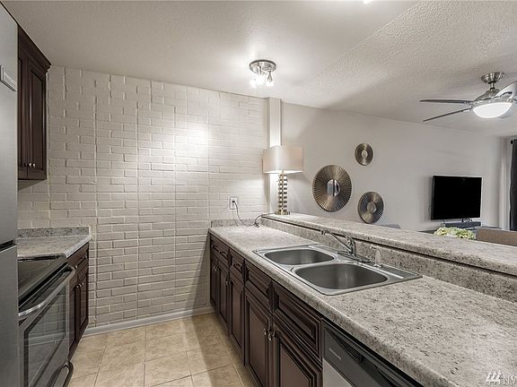 Spacious galley kitchen with charming faux brick, double sinks and plenty of cabinet and counter space.