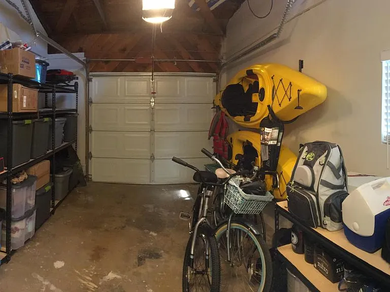 Single car garage with storage shelves (washer and dryer out of photo to the right, just inside the interior door to the garage from the back living space)