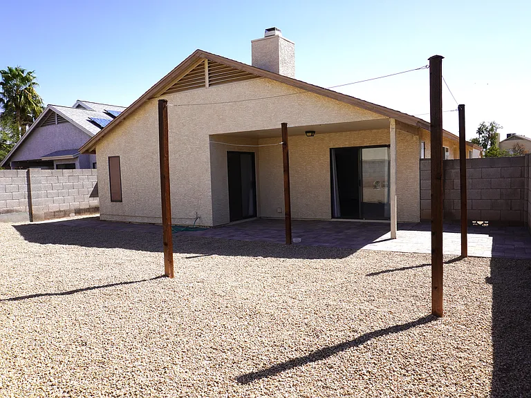 Enclosed backyard with pavers and gravel.