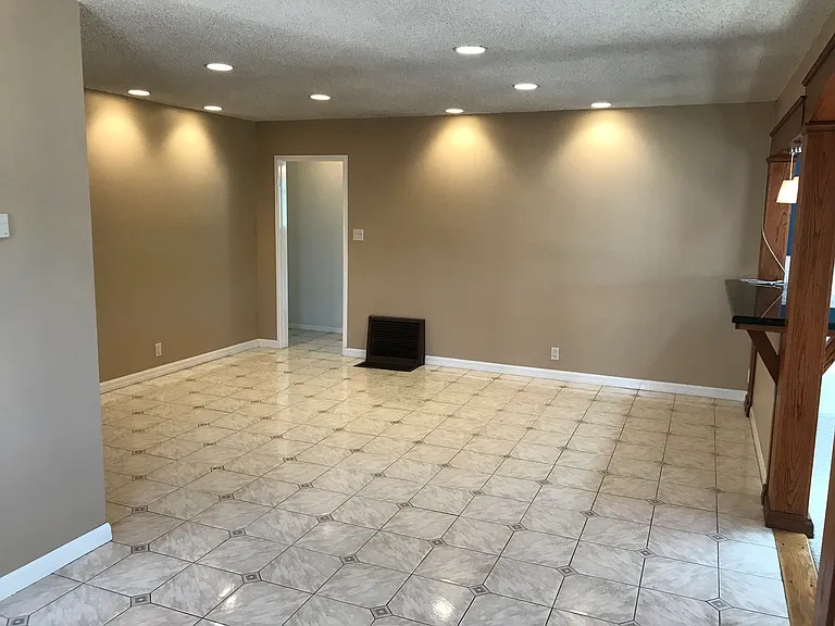 Spacious original living room with tiled floor, recessed lighting, and refurbished original 1952 Holly "Stubby" floor furnace.