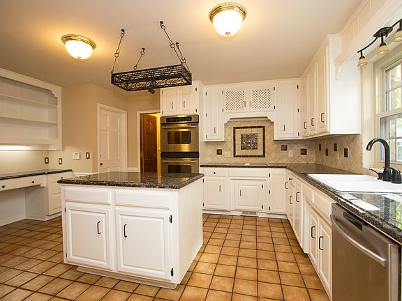 Beautifully updated granite Kitchen boasts center island, tumbled marble backsplash with decorative insets, updated hardware, lighting, oil rubbed bronze faucet and granite planning desk!