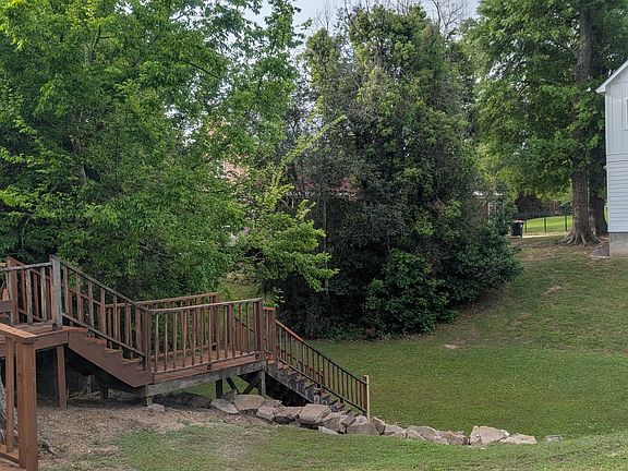 Back steps from the deck going into the backyard. The yard of this property goes into the dip and ends where the gully rises again toward the white edge of the neighbor's house