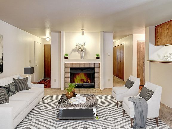 Staged and carpeted living room with fireplace.