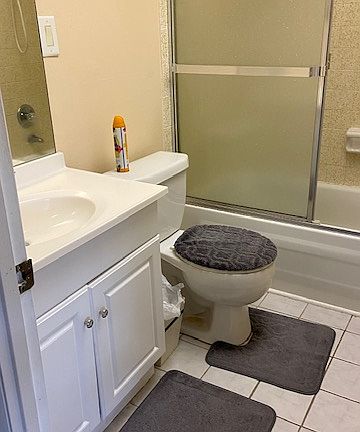 Updated bathroom with safety handle in enclosed tub.