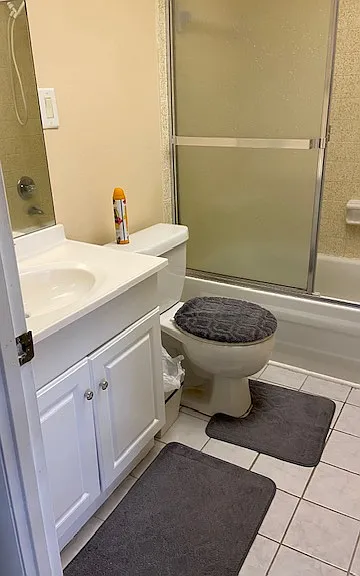 Updated bathroom with safety handle in enclosed tub.
