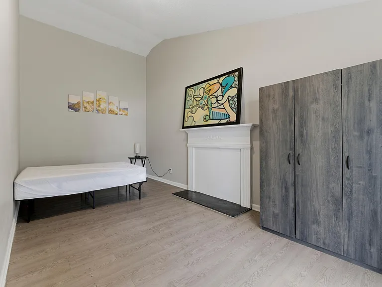 Furnished bedroom with laminate flooring, tall ceilings, and a roomy wardrobe for convenient everyday storage.