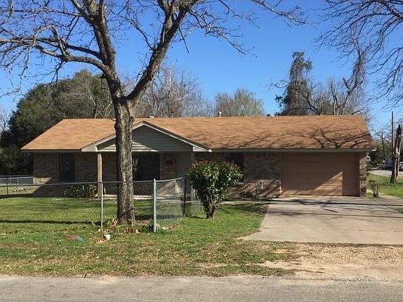 Fenced front yard has pecan tree shading it.