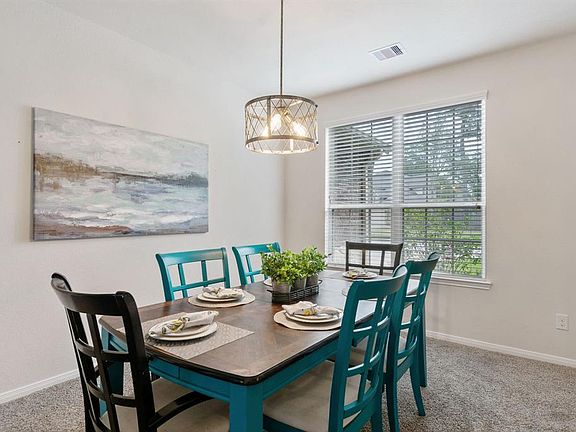 The dining room has plenty of room for a large gathering and a modern chandelier.