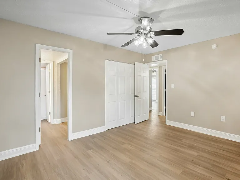 Bright and welcoming bedroom with sleek ceiling fan, fresh beige walls, and elegant wood flooring.